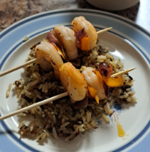 plate of rice with shrimp skewers on top