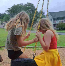 two younger girls on a tire swing